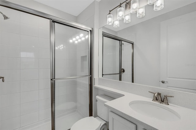 bathroom featuring a shower with door, vanity, and toilet