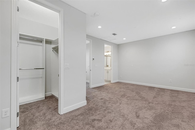 unfurnished bedroom featuring light carpet, a closet, and ensuite bath