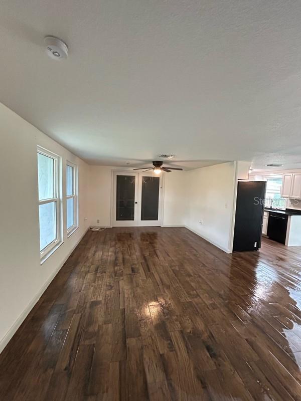 unfurnished living room with ceiling fan and dark wood-type flooring