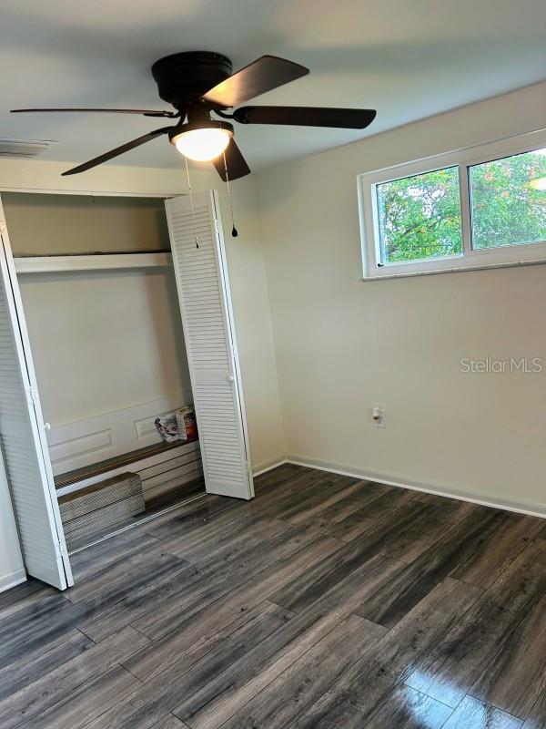 unfurnished bedroom featuring ceiling fan, a closet, and dark hardwood / wood-style flooring