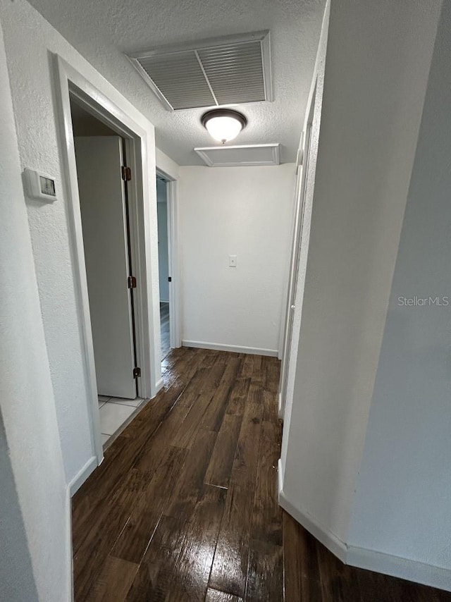 hallway featuring a textured ceiling and dark hardwood / wood-style flooring