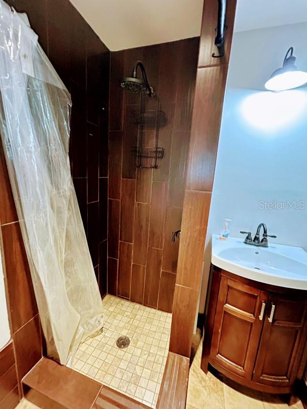 bathroom featuring walk in shower, vanity, and tile patterned floors