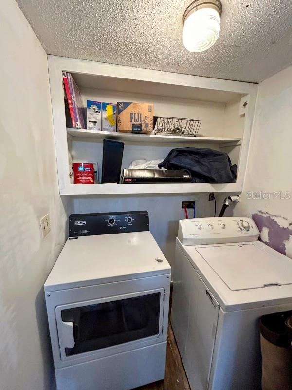 laundry room with a textured ceiling and separate washer and dryer