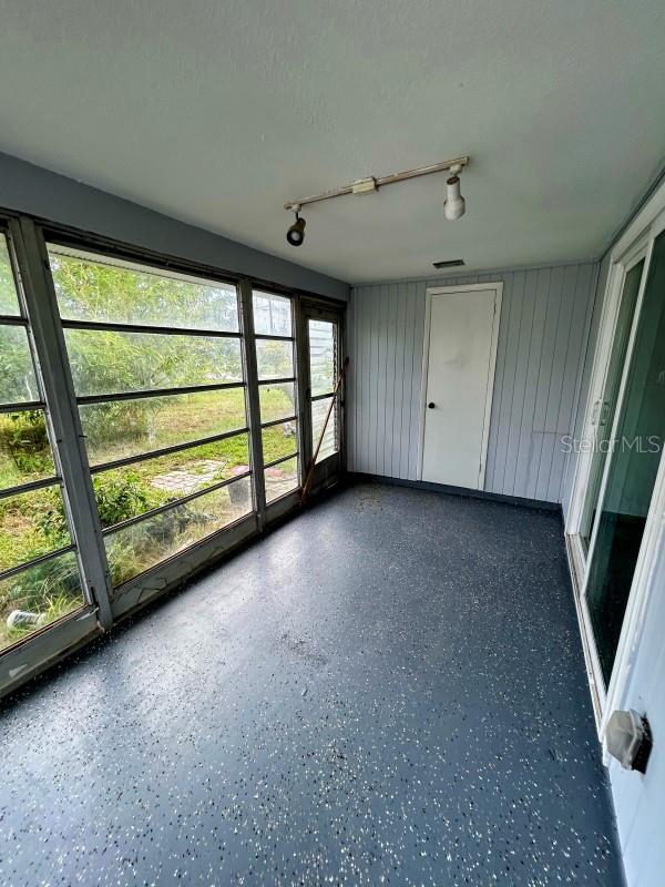 unfurnished sunroom with rail lighting