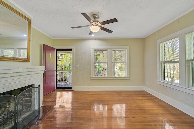 living room with wood-type flooring, a textured ceiling, a fireplace, crown molding, and ceiling fan