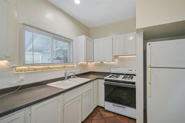1677 4th St, Sarasota, FL 34236 - kitchen with white appliances, white cabinets, a sink, dark countertops, and decorative backsplash