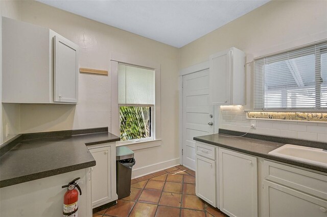 1677 4th St, Sarasota, FL 34236 - kitchen featuring white cabinets, dark tile patterned floors, dark countertops, baseboards, and backsplash