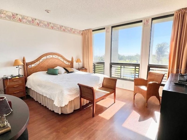 bedroom featuring a textured ceiling, expansive windows, and hardwood / wood-style flooring