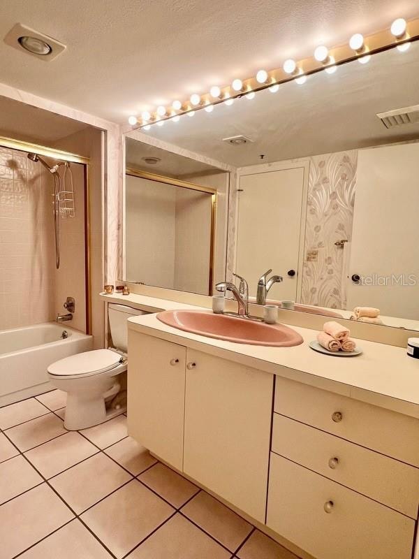 full bathroom featuring vanity, a textured ceiling, tile patterned flooring, toilet, and tiled shower / bath