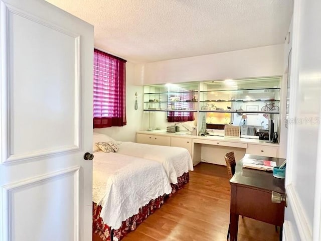 bedroom with light wood-type flooring and a textured ceiling