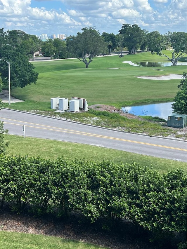 view of community with a water view, a lawn, and view of golf course