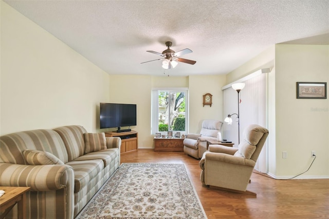 living room with a textured ceiling, ceiling fan, and light hardwood / wood-style flooring