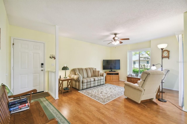 living room with ceiling fan, hardwood / wood-style flooring, and a textured ceiling