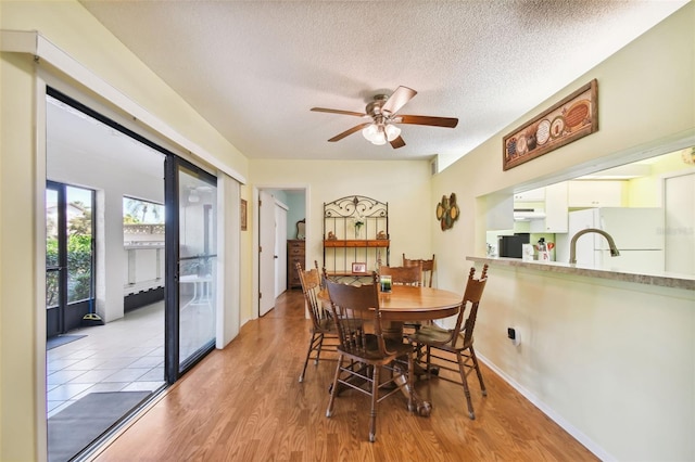 dining room with light wood-type flooring, a textured ceiling, and ceiling fan