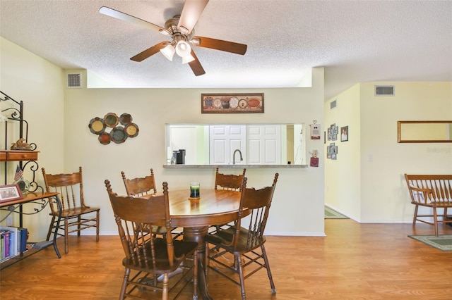 dining space with ceiling fan, a textured ceiling, and light wood-type flooring