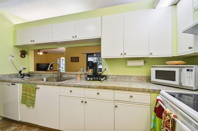 kitchen featuring white cabinets, sink, white appliances, a textured ceiling, and dark hardwood / wood-style flooring