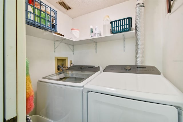 clothes washing area featuring a textured ceiling and washer and clothes dryer