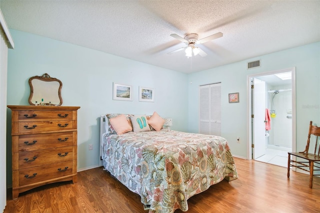 bedroom with connected bathroom, a closet, a textured ceiling, ceiling fan, and hardwood / wood-style flooring