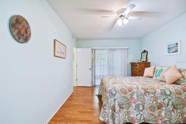 bedroom featuring light hardwood / wood-style flooring, ceiling fan, and a textured ceiling