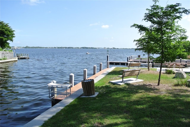 view of dock featuring a lawn and a water view