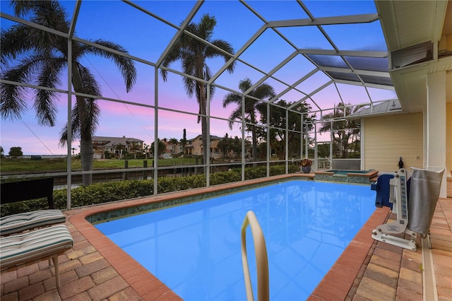 pool at dusk with an in ground hot tub, a lanai, and a patio