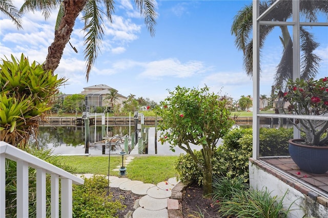 view of yard featuring glass enclosure, a dock, and a water view