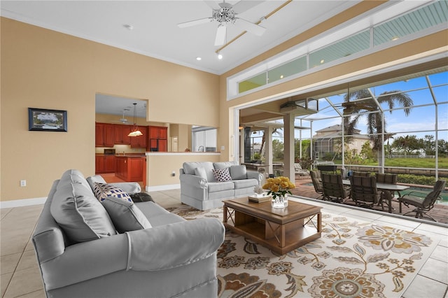 living room featuring crown molding, a towering ceiling, light tile patterned floors, and ceiling fan