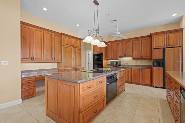 kitchen featuring decorative light fixtures, black appliances, a center island, and dark stone counters