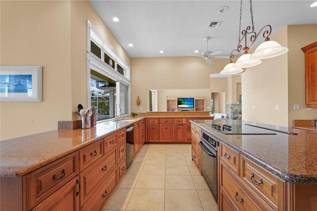 kitchen featuring decorative light fixtures, black appliances, kitchen peninsula, and dark stone countertops