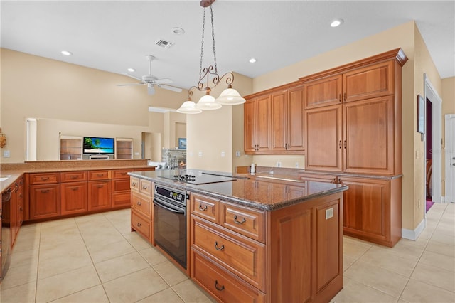 kitchen featuring black appliances, a center island, light tile patterned floors, decorative light fixtures, and dark stone counters