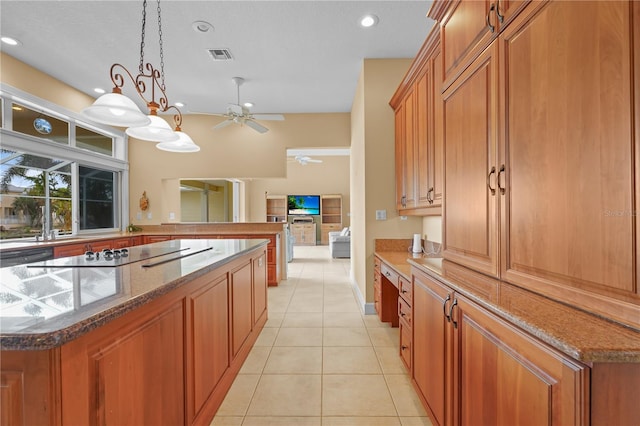 kitchen with black electric stovetop, decorative light fixtures, dark stone countertops, and light tile patterned floors