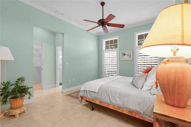 bedroom featuring a spacious closet, a closet, ceiling fan, light tile patterned floors, and crown molding