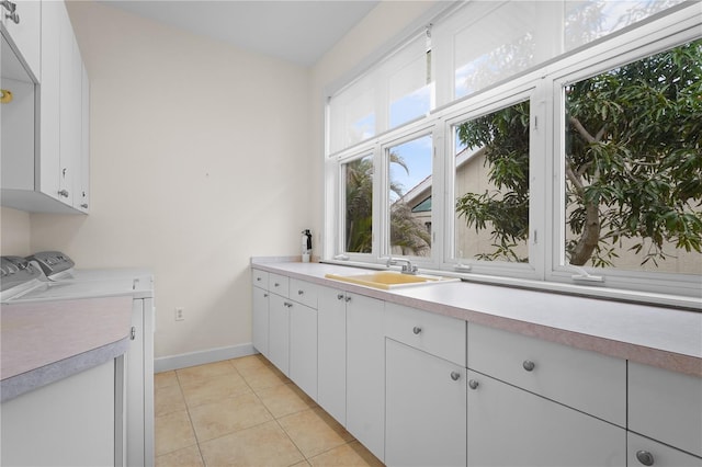 laundry room with sink, light tile patterned flooring, cabinets, and washer and dryer