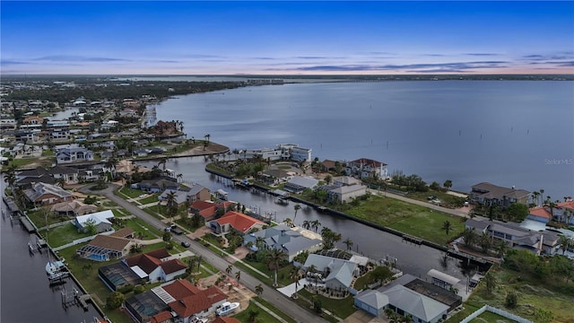 aerial view at dusk with a water view and a residential view