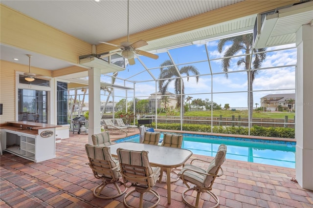 view of pool featuring glass enclosure, a patio, exterior bar, and ceiling fan