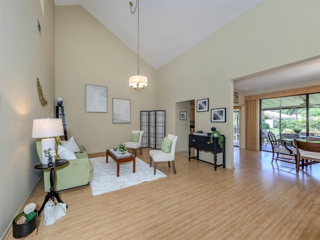 living room with high vaulted ceiling, an inviting chandelier, and light hardwood / wood-style flooring