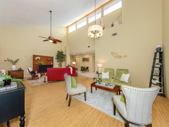 living room featuring hardwood / wood-style floors, ceiling fan with notable chandelier, and high vaulted ceiling