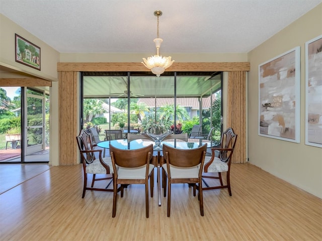 dining area featuring light hardwood / wood-style floors, a textured ceiling, and a notable chandelier