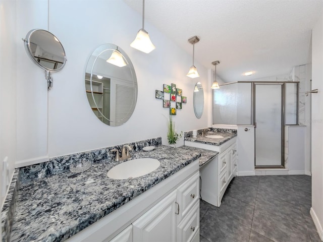 bathroom featuring tile patterned floors, vaulted ceiling, a textured ceiling, vanity, and a shower with shower door