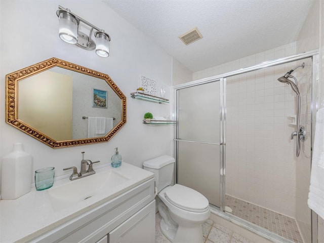 bathroom with toilet, vanity, a textured ceiling, and a shower with door