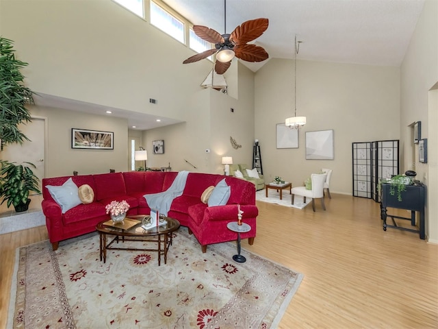 living room featuring hardwood / wood-style floors, ceiling fan with notable chandelier, and high vaulted ceiling