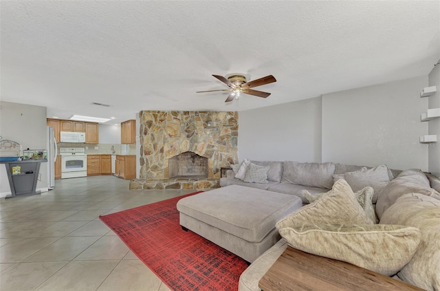 living room featuring a fireplace, light tile patterned floors, a textured ceiling, ceiling fan, and sink