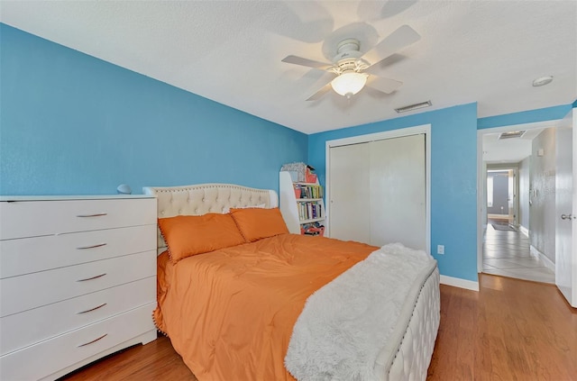 bedroom with a closet, wood-type flooring, ceiling fan, and a textured ceiling