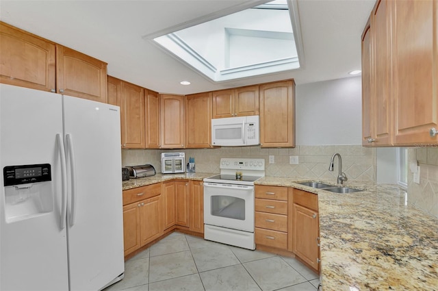 kitchen featuring light stone counters, tasteful backsplash, sink, white appliances, and a skylight