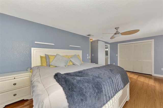 bedroom with light hardwood / wood-style flooring, a closet, ceiling fan, and a textured ceiling