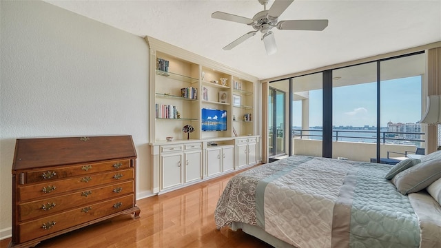 bedroom with ceiling fan, a wall of windows, light hardwood / wood-style flooring, and access to exterior