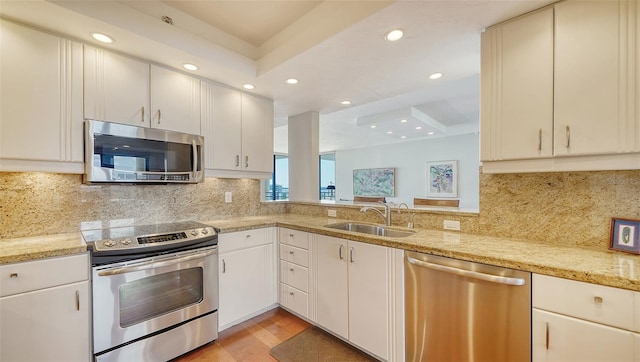 kitchen featuring sink, white cabinetry, appliances with stainless steel finishes, light stone countertops, and light hardwood / wood-style floors