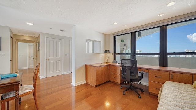 home office featuring a textured ceiling and light hardwood / wood-style flooring