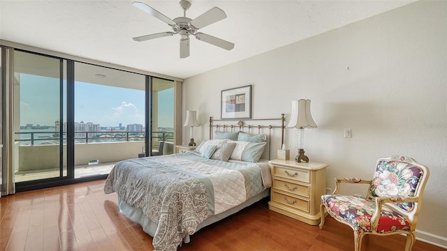 bedroom featuring ceiling fan, a wall of windows, access to exterior, and hardwood / wood-style floors