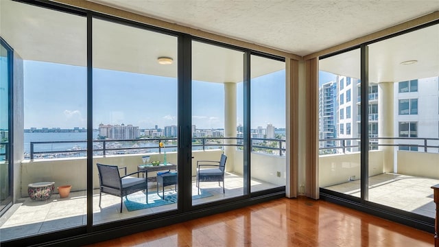 interior space featuring a water view, expansive windows, and hardwood / wood-style flooring